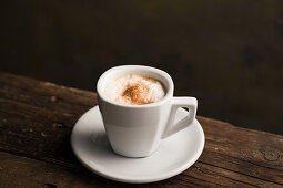 Cappuccino in weisser Tasse auf Holztisch