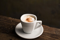 From above delicious fragrant brown beverage with white foam in ceramic cup on wooden table