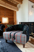 Armchair with tartan seat and embroidered leather backrest in front of fireplace