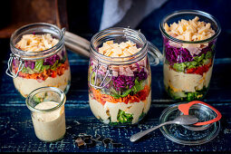 Layered salad in a jar - broccoli, eggs, sauce, peper, carrot, lettuce, purple cabbage, ham, cheese