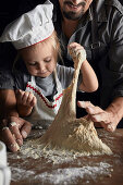 Father and daughter kneading the dough together