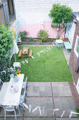 Terrace area and lawn surrounded by brightly painted walls in courtyard garden