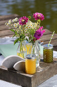 Picknick am See mit Getränken, Dekofischen und Blumen in Glasflaschen