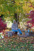 Upturned wine crates as a seating area under the maple tree, woman with a teacup, with Zula the dog