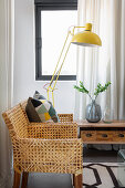 Yellow standard lamp next to cane chair