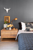 Bed and wooden bedside cabinet against slate-grey wall