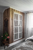 DIY fitted wardrobe made from dark wood with glass doors backed by gathered fabric