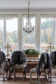 Grey sheepskin rugs on chairs around dining table in conservatory