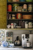 Old tin cans and crockery on kitchen shelves above coffee machine
