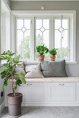 Chest bench below window in hallway with pale grey walls