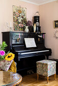 Piano and stool in corner of room with pink walls