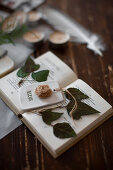 Pendant with fabric flower and pressed ivy leaves in open book