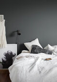 Plate of biscuits on bed with white bed linen, reading lamp on grey wall and black-and-white photograph