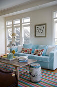 Bunt gestreifter Teppich und hellblaues Sofa im exotischen Wohnzimmer