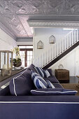 Blue sofa in interior with staircase and silver stucco ceiling