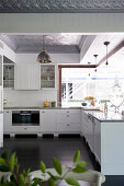 L-shaped kitchen counter with white base units in open-plan kitchen with dark wooden floor