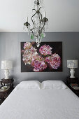 Floral artwork above double bed flanked by lamps on bedside tables