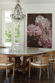 Table with marble top and chairs in front of floral artwork in dining area