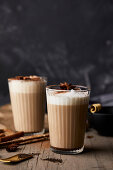 Chai latte in glasses with milk foam and anise stars