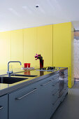 Modern kitchen counter and yellow floor-to-ceiling cupboards in architect-designed house