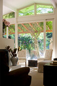 View from interior through sliding doors and onto terrace with climbing plants growing over pergola