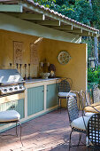 Roofed outdoor kitchen with barbecue on terrace in vintage country-house style