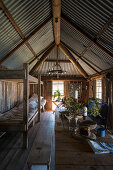 Beds next to dining table with wooden bench in simple wooden cabin