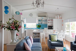 Blue-and-white interior with open-plan kitchen and seating area with couch and armchairs