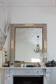 Mirror with ornate wooden frame on white marble mantelpiece