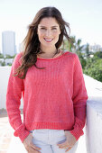 A young woman wearing a fuchsia jumper and white jeans