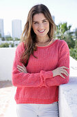 A young woman wearing a fuchsia jumper and white jeans