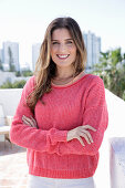 A young woman wearing a fuchsia jumper and white jeans