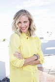 A blonde woman wearing a frilly yellow blouse