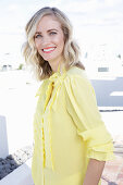 A blonde woman wearing a frilly yellow blouse