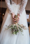 Bride holding bridal bouquet behind back