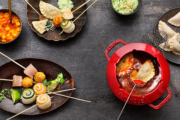 Fondue with a spicy broth: fish and vegetable rolls, chicken and pastry parcels