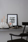 Framed motto and camera on grey desk with black chair