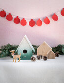 Winter arrangement of nesting box, fir cones, reindeer figurine and garland