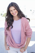 A young woman with long hair wearing a purple t-shirt and a wrap-around jumper