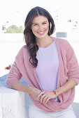 A young woman with long hair wearing a purple t-shirt and a wrap-around jumper