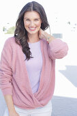 A young woman with long hair wearing a purple t-shirt and a wrap-around jumper