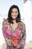 A brunette woman wearing a colourful beach dress