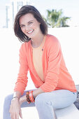 A young woman wearing an apricot top, cardigan and jeans