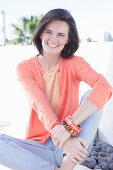 A young woman wearing an apricot top, cardigan and jeans