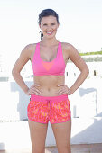 A young woman wearing a pink sports bra and patterned shorts