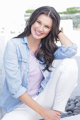 A young woman wearing a purple t-shirt, a denim shirt and white trousers