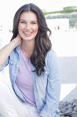 A young woman wearing a purple t-shirt, a denim shirt and white trousers