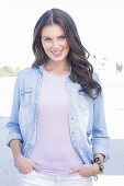 A young woman wearing a purple t-shirt, a denim shirt and white trousers