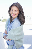 A young woman wearing a denim shirt with a jumper over her shoulders