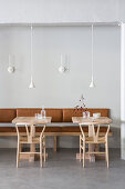 Designer chairs and small tables against leather bench in restaurant